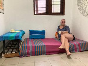 Hostel Singha Lounge في يوناواتونا: امرأة تجلس على سرير مع كوب من القهوة