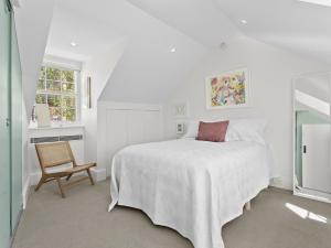 a white bedroom with a bed and a chair at WIND82D - Windmill at Dawes in Sydney