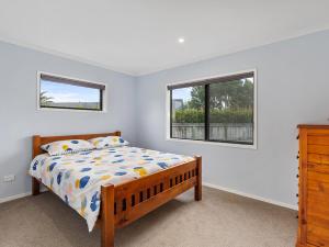 a bedroom with a bed and two windows at Mangawhai Monarch - Mangawhai Heads Holiday Home in Mangawhai