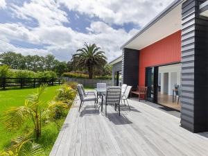 a deck with chairs and a table on a house at Mangawhai Monarch - Mangawhai Heads Holiday Home in Mangawhai