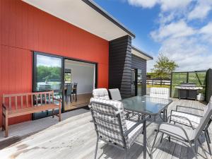 a patio with a table and chairs on a deck at Mangawhai Monarch - Mangawhai Heads Holiday Home in Mangawhai