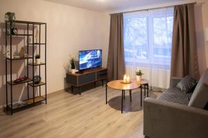 a living room with a couch and a tv and a table at Studio apartamenti in Alūksne