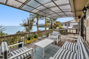 een patio met stoelen en tafels en uitzicht op de oceaan bij Coopers Sands - Coopers Beach Holiday Home in Coopers Beach