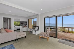 sala de estar con sofá y vistas al océano en Coopers Sands - Coopers Beach Holiday Home, en Coopers Beach