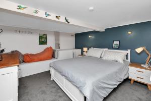 1 dormitorio con 1 cama blanca y paredes azules en Coopers Sands - Coopers Beach Holiday Home, en Coopers Beach