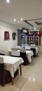 a dining room with white tables and white chairs at Гостиница ,,Меркурий и К,, in Astana