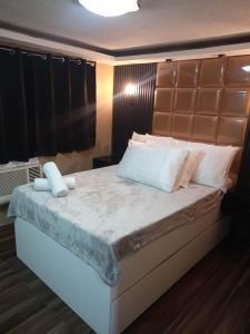 1 dormitorio con 1 cama grande con almohadas blancas en IV’s Condo w/ Netflix and Wi-Fi, en Cainta