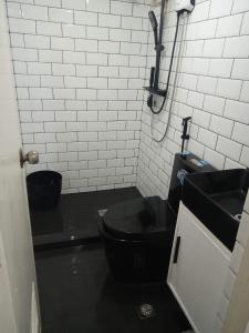 baño con aseo negro y lavamanos en IV’s Condo w/ Netflix and Wi-Fi, en Cainta