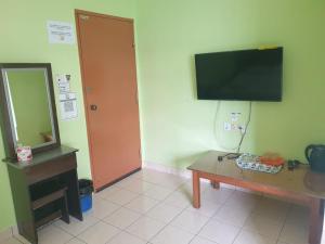 Habitación con mesa, espejo y TV. en Borneo Gaya Lodge en Kota Kinabalu