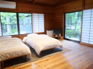 two beds in a room with windows at Forest Villa Yamanakako in Yamanakako