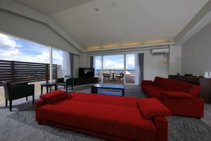 a living room with a red couch and a large window at Terrace Garden Mihama Resort by Coldio Premium in Chatan