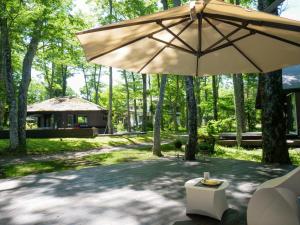 山中湖的住宿－Forest Villa Yamanakako，一个带遮阳伞的庭院和一座建筑