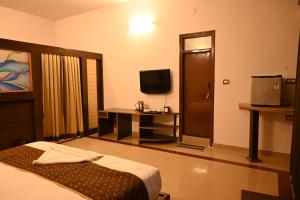 ein Hotelzimmer mit einem Bett und einem TV in der Unterkunft Advaitha Serenity Resorts in Kālvādi