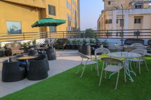 a patio with tables and chairs and an umbrella at Four Leaf Hotel - Sapphire Blue, Varanasi in Varanasi