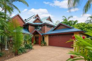 a large house with a red garage at ZenLux: 3-Story Corporate Golf Retreat + Pool/BBQ in Knuckeys Lagoon