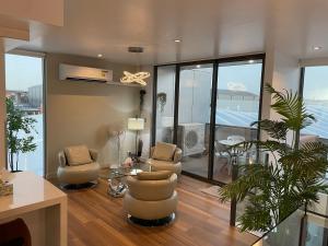 a living room with chairs and a table and windows at Docklands Luxury Penthouse Right Above The District Docklands in Melbourne