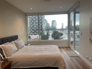 a bedroom with a bed and a large window at Docklands Luxury Penthouse Right Above The District Docklands in Melbourne