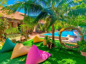 a group of colorful pillows sitting on the grass near a pool at MAY Bungalow in Mui Ne