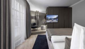a hotel room with a bed and a tv on a wall at Hotel Weisses Roessl in Kitzb&uuml;hel