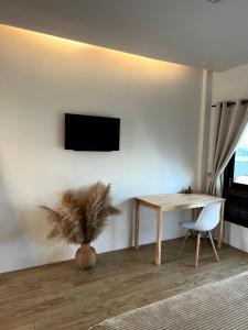 Centerpoint Koh Phangan New في تونغسالا: غرفة معيشة مع طاولة وتلفزيون على الحائط