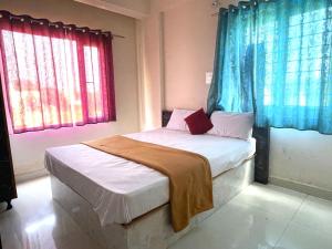 a small bed in a room with two windows at STAYMAKER CP Residency in Mysore