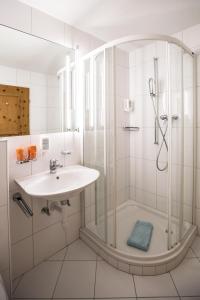 a white bathroom with a sink and a shower at Hotel Chalamandrin in Ftan
