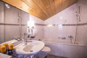a bathroom with a sink and a toilet and a tub at Hotel Chalamandrin in Ftan +23 photos