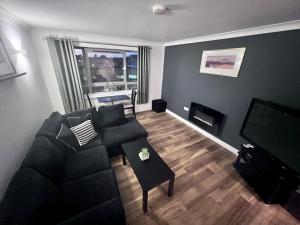 ein Wohnzimmer mit einem Sofa und einem TV in der Unterkunft Cydel Court in Kidlington