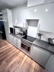 una cocina con armarios blancos y electrodomésticos de acero inoxidable en Cydel Court en Kidlington