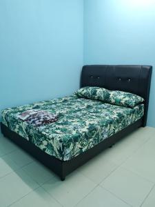 een bed met een zwart frame en een groen dekbed bij HOMESTAY ALFARUQI GAMBANG (5) in Kampong Pohoi