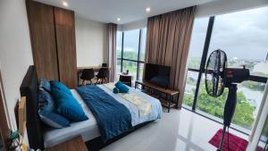 a bedroom with a bed with blue pillows and a television at Comfy Studio Kuching in Kuching