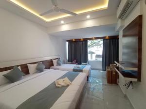 una camera d'albergo con due letti e una televisione di Royal N Deluxe a Bangalore