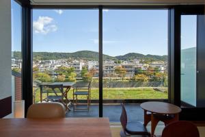 Genji Kyoto, a Member of Design Hotels في Giommachi: غرفة مع طاولة وكراسي ونافذة كبيرة