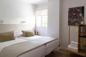 Cama blanca en habitación con ventana en Alojamientos Rurality Home, en La Alberca