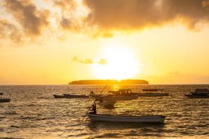 a group of boats in the water at sunset at The Mora Zanzibar - Luxury All Inclusive in Matemwe