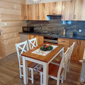 a kitchen with a wooden table with chairs and a stove at Domek u Stolarza in Grywałd +30 photos