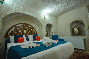 a bedroom with a large bed with blue and white sheets at Milagre Cave Hotel in Göreme