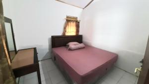 Un pequeño dormitorio con una cama rosa en una habitación en Villa Family Pantai Citepus Pelabuhanratu en Citepus