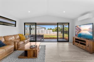 un salon avec un canapé et une télévision dans l'établissement Whai Awa Retreat - Mangawhai Holiday Home, à Mangawhai