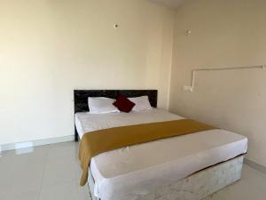 a small bedroom with a bed with a red pillow at STAYMAKER CP Residency in Mysore