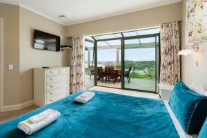 um quarto com uma cama azul e uma varanda em Swallows Nest - Paihia Holiday Home em Paihia