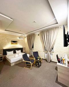 タシュケントにあるAl Arda HOTELのベッド1台、椅子2脚、テレビが備わる客室です。