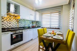 cocina con mesa de madera y sillas amarillas en Fera Life Suit Apart, en Trabzon