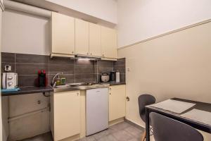 a small kitchen with white cabinets and a table at Simple in Athens