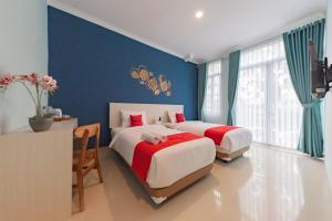 two beds in a bedroom with blue walls and a desk at RedDoorz Plus near Surapati Core in Bandung
