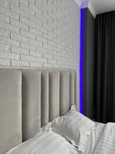 a bed with white pillows and a brick wall at Апартаменты люкс класса in Pavlodar