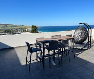 einen Tisch und Stühle auf einer Terrasse mit Meerblick in der Unterkunft Gerriviews Penthouse Seaview in Gerringong