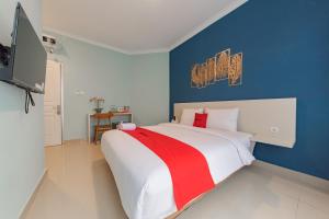 a bedroom with a large bed with a blue wall at RedDoorz Plus near Surapati Core in Bandung