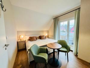 a bedroom with a bed and two chairs and a table at Haus Nordlicht in Ahrenshoop