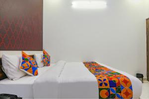 ein Schlafzimmer mit einem weißen Bett und bunten Kissen in der Unterkunft FabExpress SS Grand in Banthra Sikandarpur